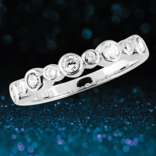 Manhattan Stacker D sterling silver ring for female featuring a row of bezel-set round white gemstones against a sparkling dark blue background.