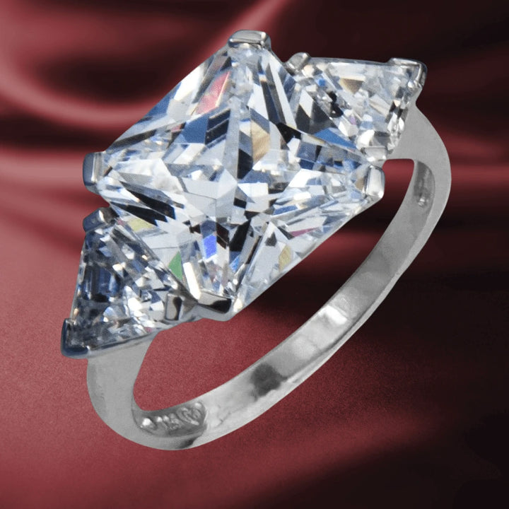 Legend Ring featuring a large princess-cut center stone flanked by two smaller stones set in sterling silver with rhodium plating, designed for women’s jewelry.