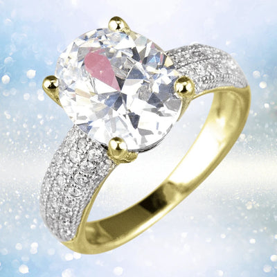 Caravella Gold Ring featuring a large clear oval gemstone centerpiece set in sterling silver with gold-tone prongs and a band encrusted with smaller sparkling stones for an elegant look.