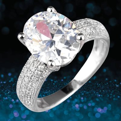 Caravella Rhodium Ring featuring a large oval clear gemstone set in sterling silver with rhodium plating and pavé accents on the band, designed for women’s jewelry collections.