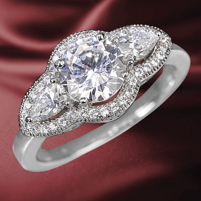 Oleander Ring featuring a sterling silver band plated in rhodium, adorned with a large central round-cut stone and two pear-shaped stones surrounded by smaller sparkling accents.