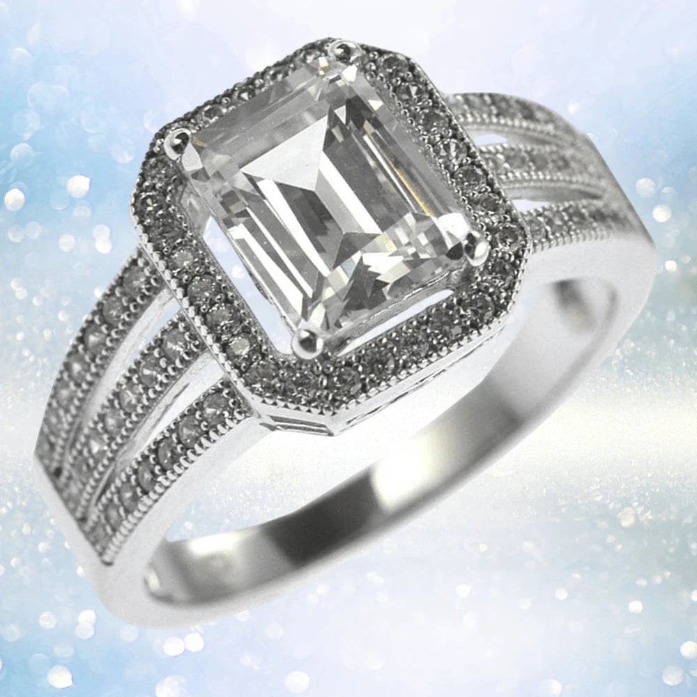 Artica Ring featuring a sterling silver band with rhodium plating, showcasing a large emerald-cut clear gemstone surrounded by smaller stones, designed for women’s jewelry.