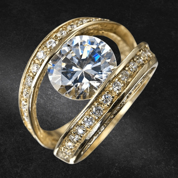 Strata Ring featuring a sterling silver band with gold plating, accented by a large central sparkling stone and smaller clear stones along the swirling band, designed for women.