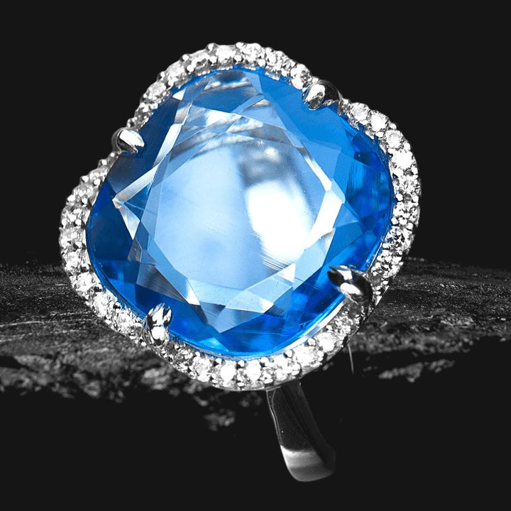 Ice Lake Ring featuring a large blue gemstone encircled by sparkling stones set in sterling silver with rhodium plating, designed for female jewelry elegance.