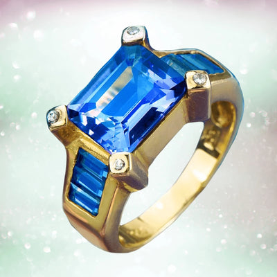 Cleopatra Topaz Ring featuring a large rectangular blue topaz gemstone set in gold-plated sterling silver with four small accent stones, designed for women’s jewelry.