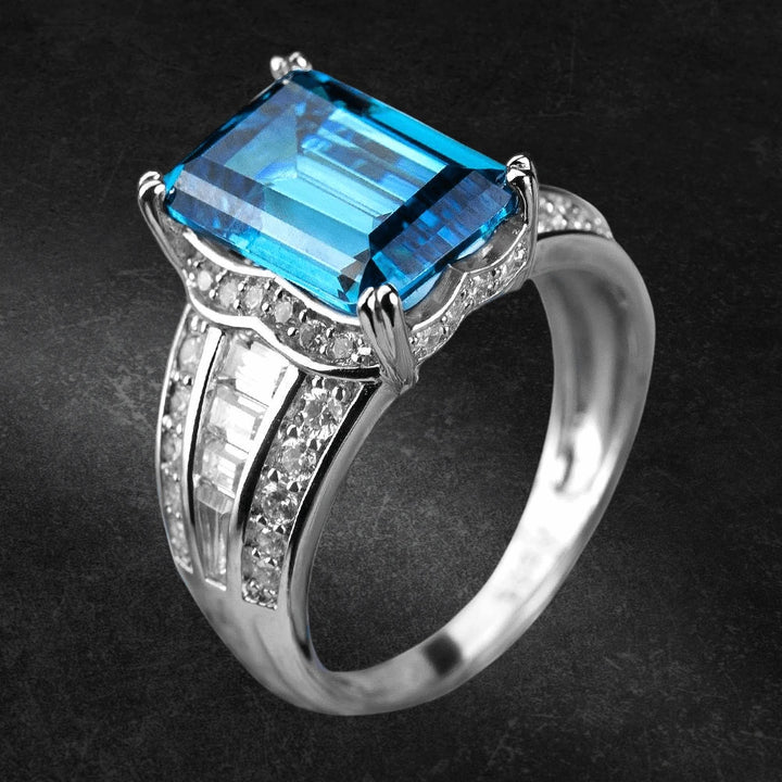 Orianna Rhodium Ring featuring a large rectangular blue gemstone set in sterling silver with rhodium plating and accented with smaller clear stones, designed for women.