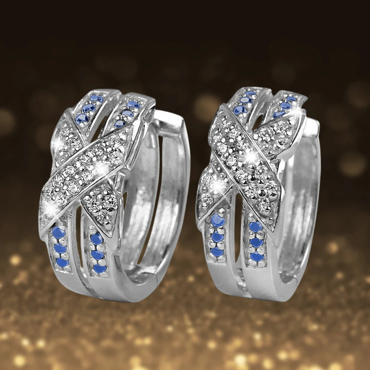 Embrace Rhodium Earrings crafted from sterling silver with rhodium plating, featuring intertwined bands adorned with clear and blue gemstones for a refined feminine style.