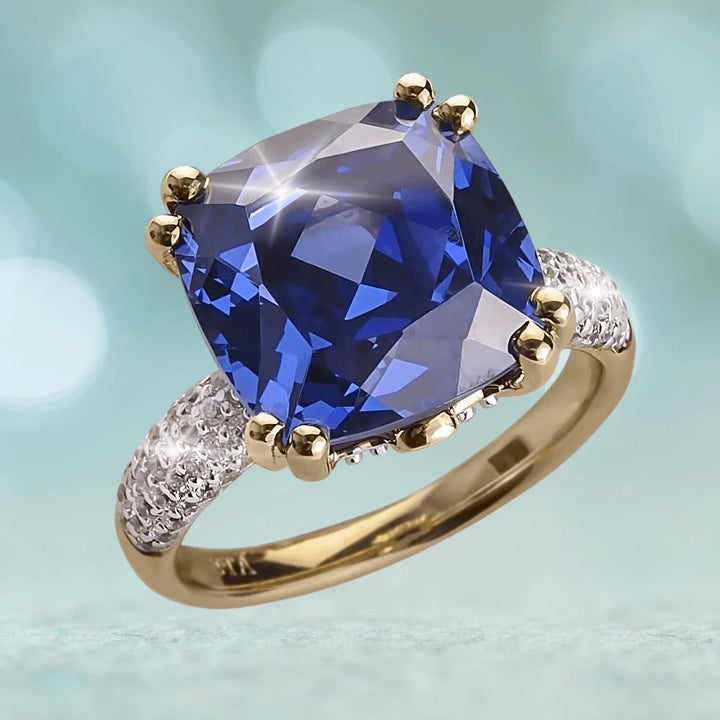 Helena Ring featuring a large cushion-cut blue gemstone set in gold-plated sterling silver with pavé diamond accents, designed for women’s elegant jewelry collections.