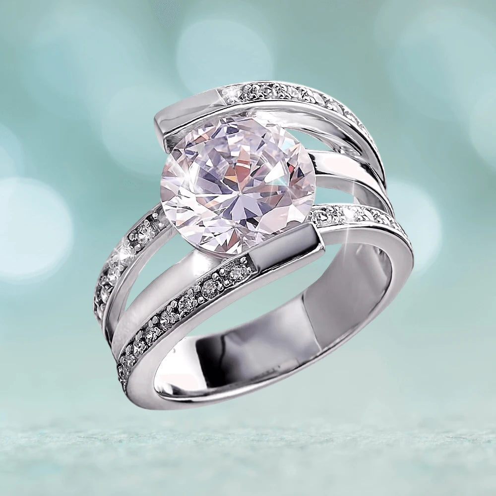 Rodela Rhodium Ring designed for women, featuring sterling silver with rhodium plating and a large clear stone centerpiece accented by smaller sparkling stones along the band.