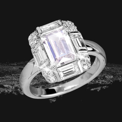 Miami Deco Ring featuring a sterling silver band with rhodium plating, showcasing a large emerald-cut central stone surrounded by baguette and round clear gemstones, designed for female jewelry enthusiasts.