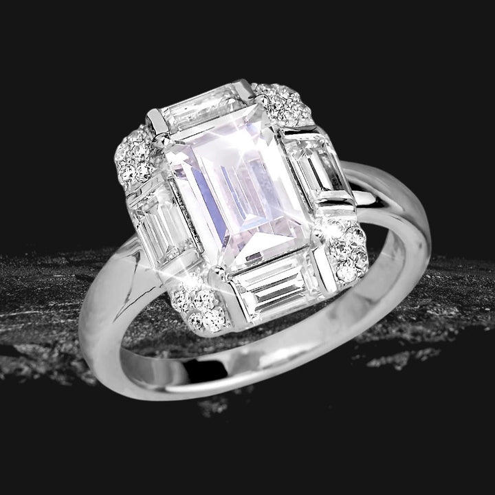 Miami Deco Ring featuring a sterling silver band with rhodium plating, showcasing a large emerald-cut central stone surrounded by baguette and round clear gemstones, designed for female jewelry enthusiasts.