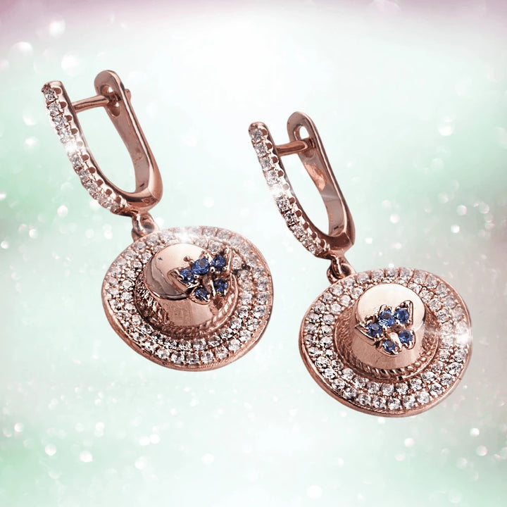 Memories Of Summer Earrings crafted from sterling silver with rose gold plating, featuring a circular design adorned with sparkling crystals and blue gemstone accents.