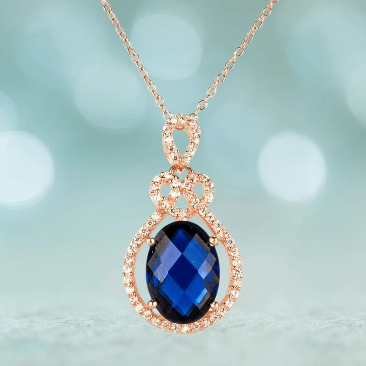 Rosa De Mer Pendant featuring a sterling silver setting plated in rose gold, showcasing a deep blue faceted gemstone surrounded by sparkling accents, elegant jewelry for women.