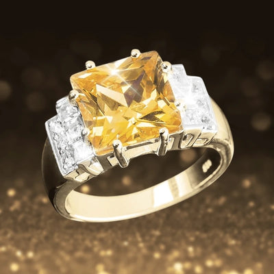 Princetta Canaria Ring featuring a gold-plated sterling silver band with a large faceted yellow gemstone centerpiece and smaller clear stones on each side, designed for women.