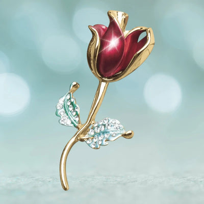 Elegant Rosea Brooch featuring a gold-tone rose with a deep red enamel bloom and sparkling crystal-accented green leaves, designed for female jewelry collections.