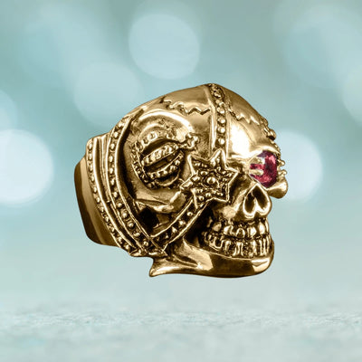 Riotous Skull Ring crafted in gold-plated stainless steel featuring a detailed skull design with a red gemstone eye, a bold jewelry piece for male fashion.