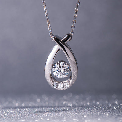 Silver teardrop-shaped pendant with a diamond on a gray background