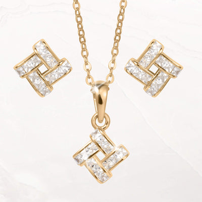 Gold tone geometric jewelry set with matching drop earrings and a pendant necklace featuring clear faceted stones on a white background