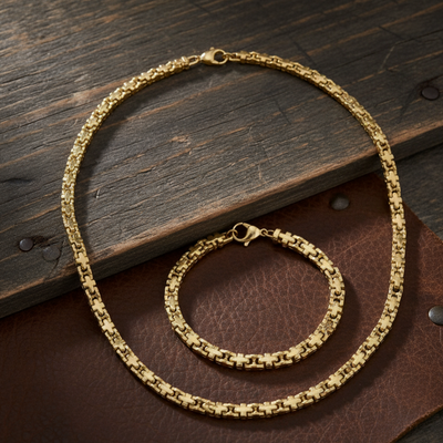 Gold chain necklace and bracelet on a wooden surface