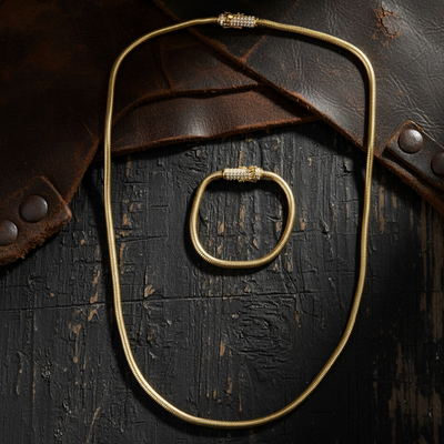 Gold necklace on a textured dark surface with leather accents