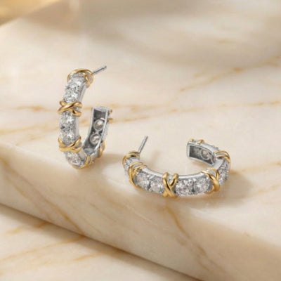Pair of gold and silver hoop earrings on a beige marble surface