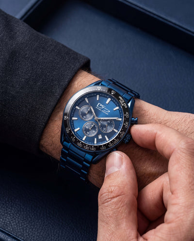 Close-up of a hand adjusting the Midnight Velocity Men's Watch with a sleek blue metal band and chronograph dial, showcasing a modern design ideal for stylish watch collectors.