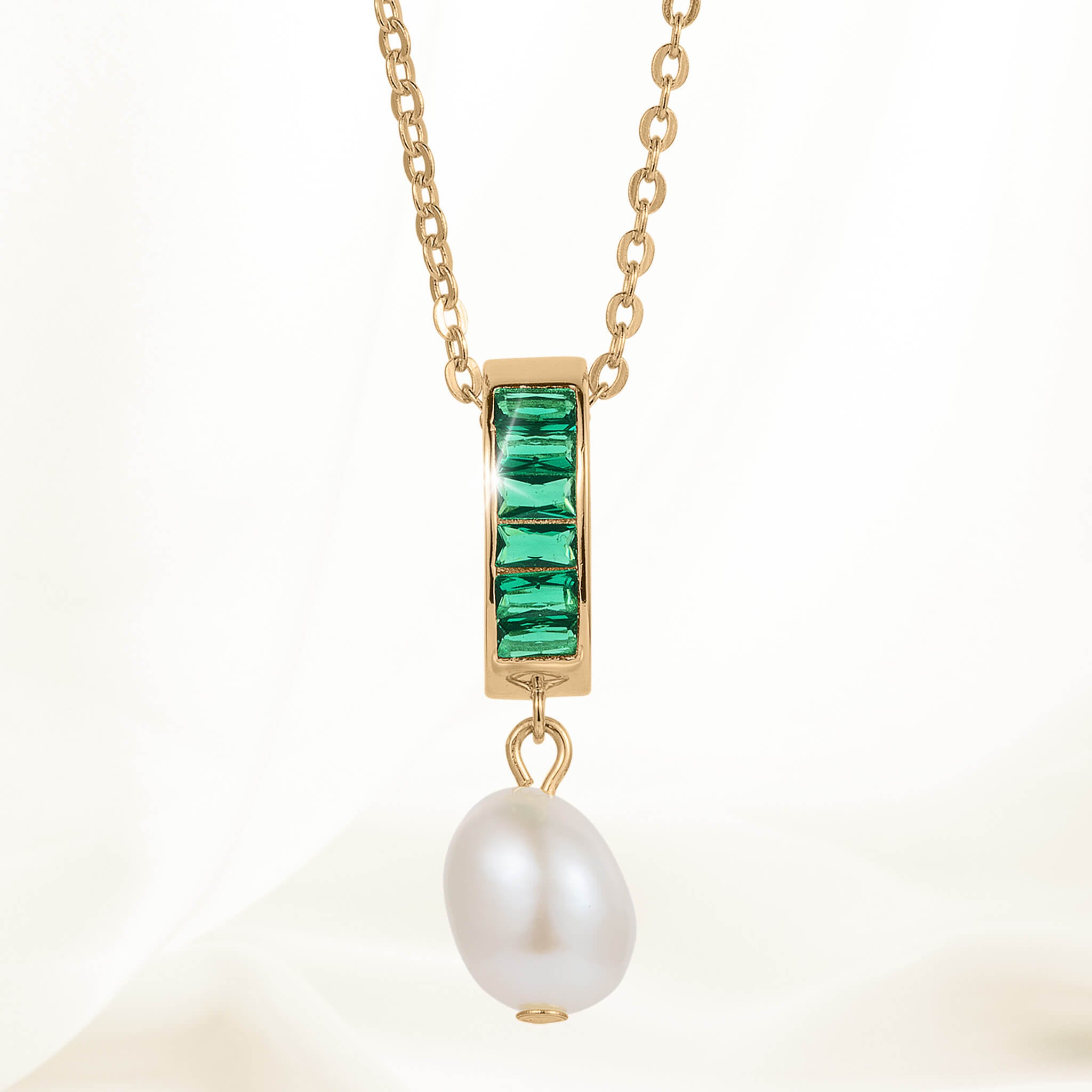 Elegant gold chain necklace featuring a rectangular pendant with green gemstones and a dangling white pearl from the Pearl Radiance Collection