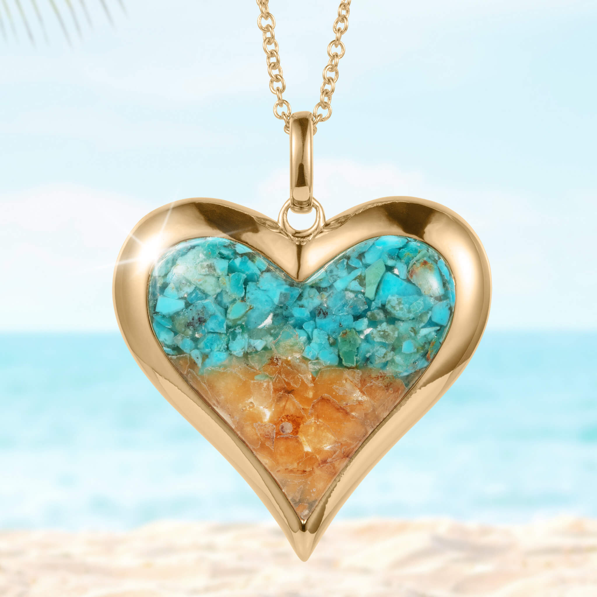 Sunlit Shore Heart Pendant featuring a gold-tone heart-shaped frame with turquoise and amber stone inlays on a delicate chain, set against a beach background.