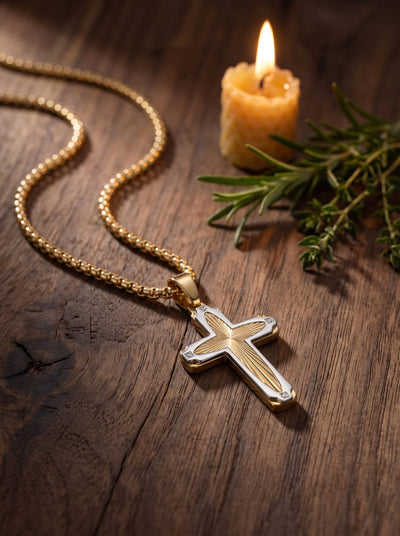 Guiding Light Cross Pendant displayed on a wooden surface beside a lit candle and greenery showcasing its detailed gold tone cross design and elegant jewelry styling