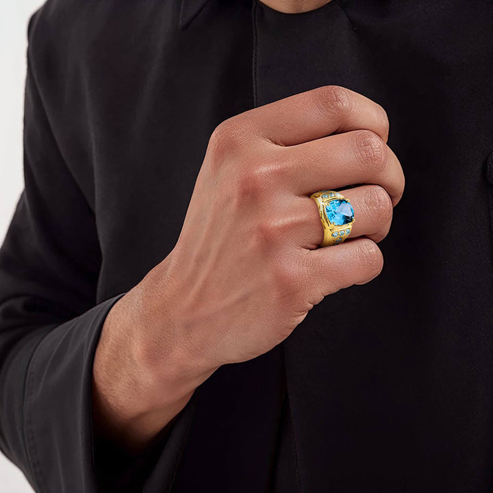 Mediterranean Blue Topaz Ring featuring a large blue topaz gemstone set in gold-plated sterling silver, worn on a man's hand with a black long-sleeve outfit, showcasing elegant jewelry.