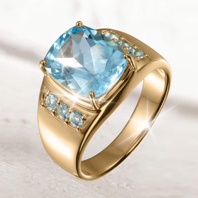 A luxurious Aegean Blue Topaz Men's Ring featuring a large cushion-cut blue topaz centerpiece set in a polished gold band accented with smaller blue topaz stones.