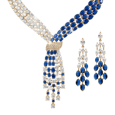 Elegant Royal Tide Collection necklace and matching earrings featuring gold settings with sparkling clear and deep blue gemstones arranged in an intricate, luxurious design.