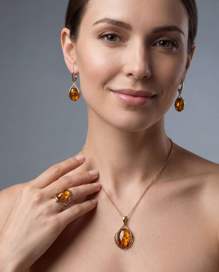 Woman wearing elegant Baltic Amber 3 Piece Set including matching teardrop-shaped amber earrings, pendant necklace, and ring, showcasing warm golden hues.