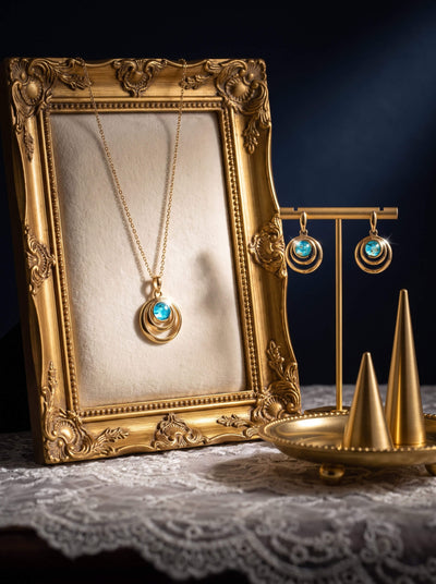 Baltic Lagoon Pendant featuring a luminous blue cabochon set in layered gold toned jewelry styled with an ornate frame and coordinating blue earrings