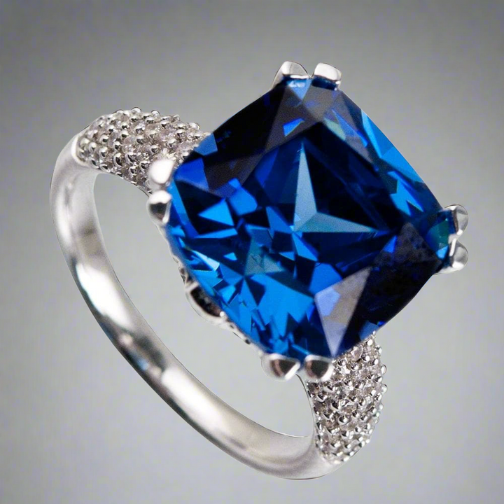 Hope Ring featuring a large square blue gemstone set in sterling silver with rhodium plating, accented by small sparkling stones on the band for elegant female jewelry.