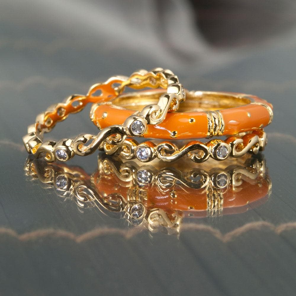 Three delicate gold rings with bright terracotta enamel and small clear stones, featuring the Ming Enamel Stacker Terracotta Rings made of sterling silver with gold plating for women.