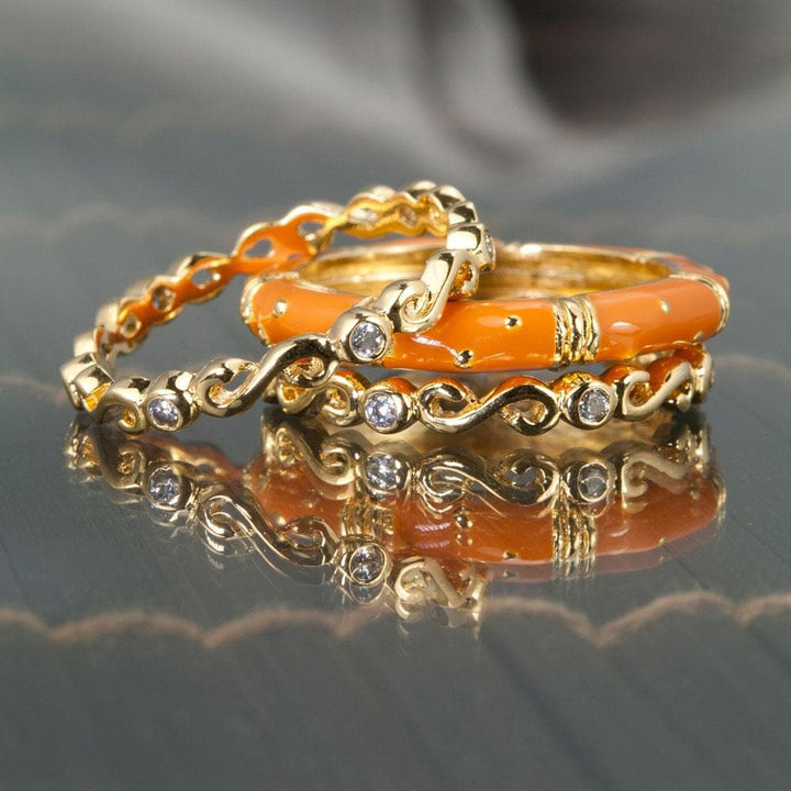 Three delicate gold rings with bright terracotta enamel and small clear stones, featuring the Ming Enamel Stacker Terracotta Rings made of sterling silver with gold plating for women.