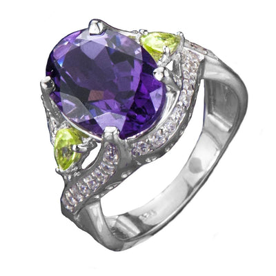 Kamira Amethyst Ring featuring a large oval amethyst center stone set in sterling silver with rhodium plating, accented by two small yellow-green gemstones and sparkling clear stones.