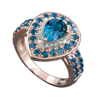 Encantada Ring in sterling silver with rose gold plating, featuring a pear-shaped blue gemstone surrounded by smaller blue and clear stones, designed for women’s jewelry.